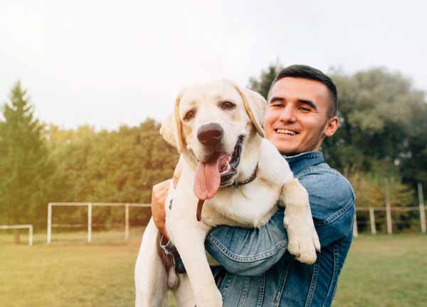 Dr. Kläffinger wie er seinen Labrador Retriever in die Kamera hält.