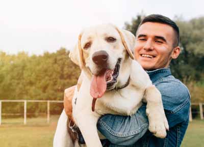Dr. Kläffinger wie er seinen Labrador Retriever in die Kamera hält.